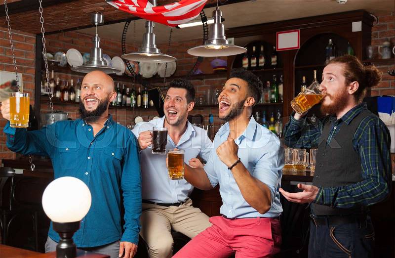 Man Group In Bar Screaming And Watching Football, Drinking Beer Hold Mugs, Mix Race Cheerful Friends Wear Shirts Meeting Pub Communicate, stock photo