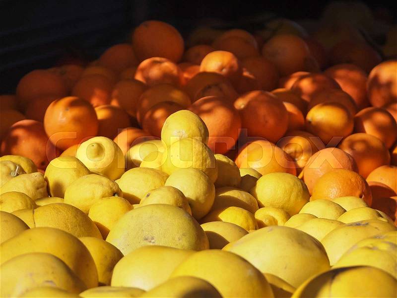 Lemons and oranges alongside each other on the market with the morning light, stock photo