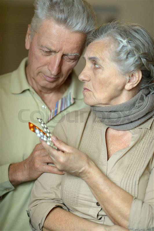 Portrait of ill senior couple with a pills, stock photo