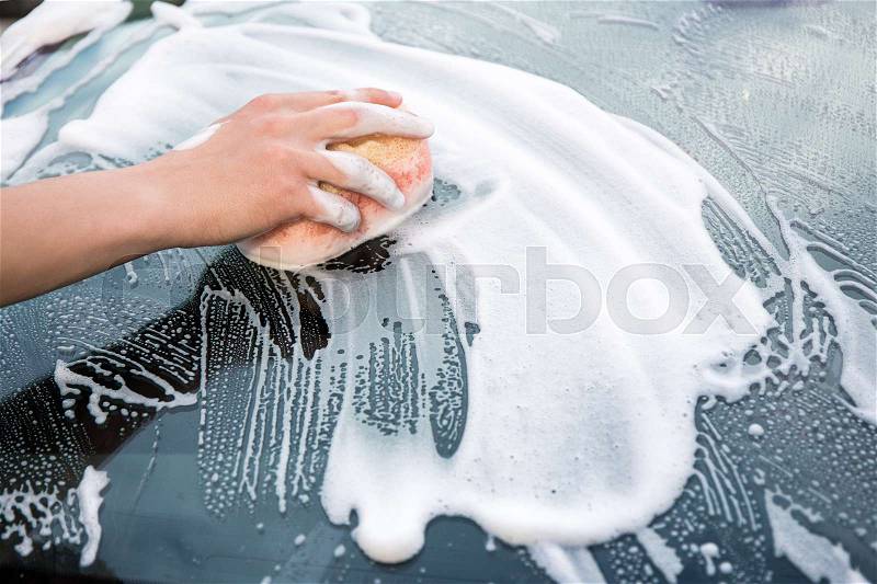 Male hand with sponge washing car window, stock photo