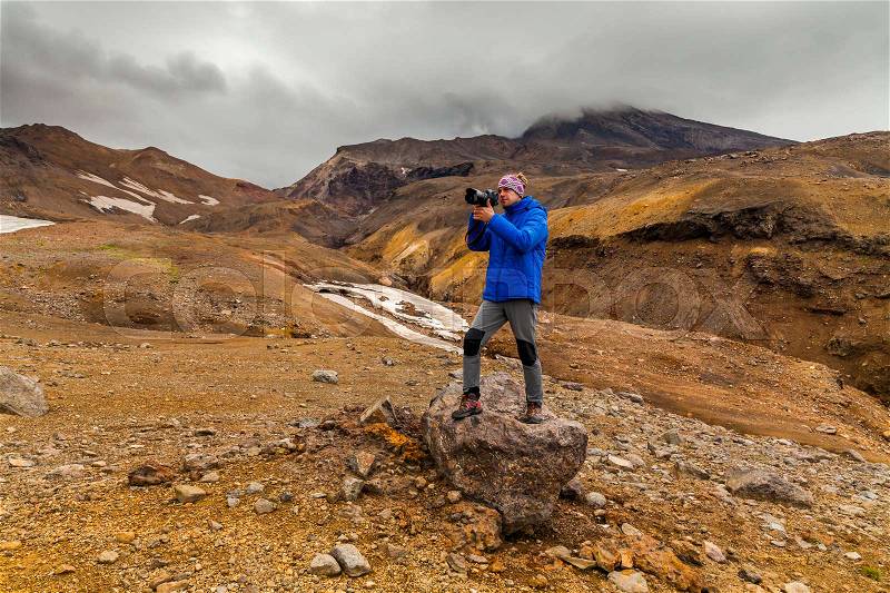 Young photographer on the background of volcanic rocks. Kamchatka, stock photo