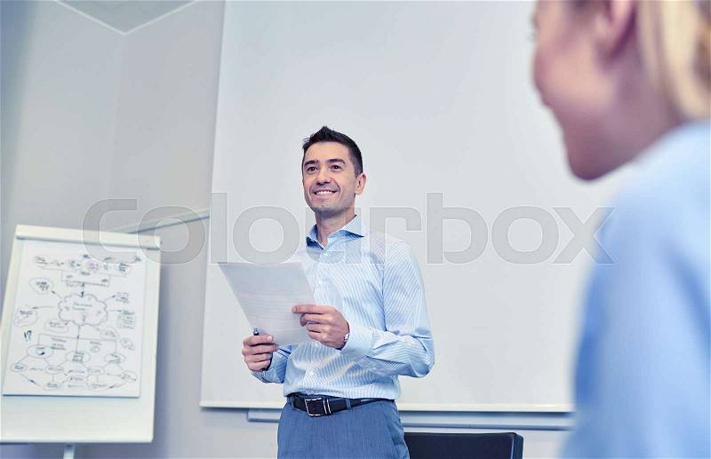 Business, people and planning concept - smiling businessman and woman with papers meeting on presentation in office, stock photo