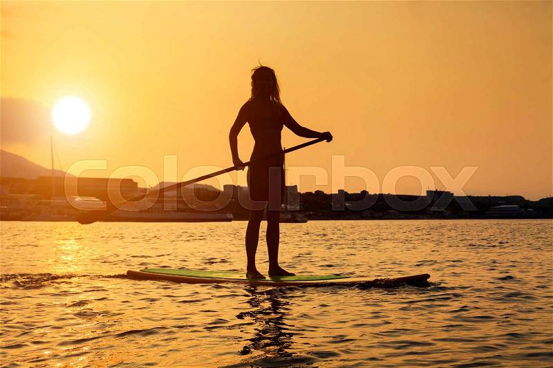 Silhouette of a beautiful woman on Stand Up Paddle Board. SUP, stock photo