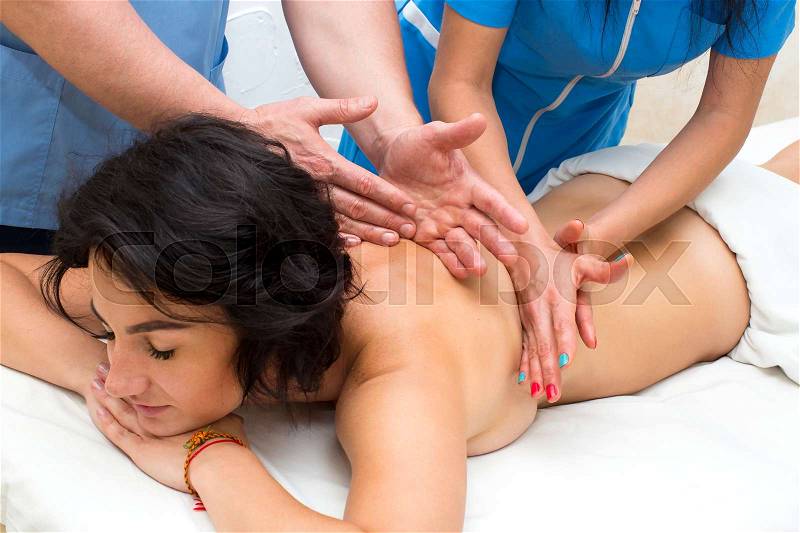 Girl on the procedure for four hands massage in the spa salon, stock photo