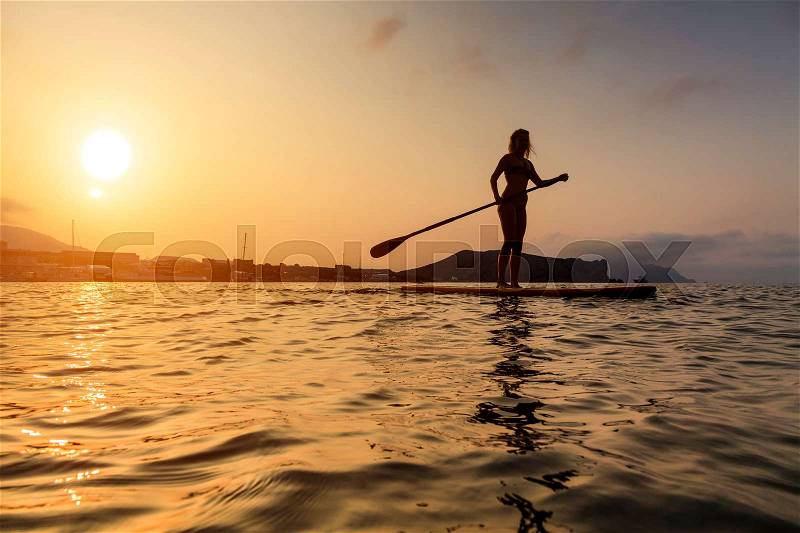 Silhouette of a beautiful woman on Stand Up Paddle Board. SUP, stock photo