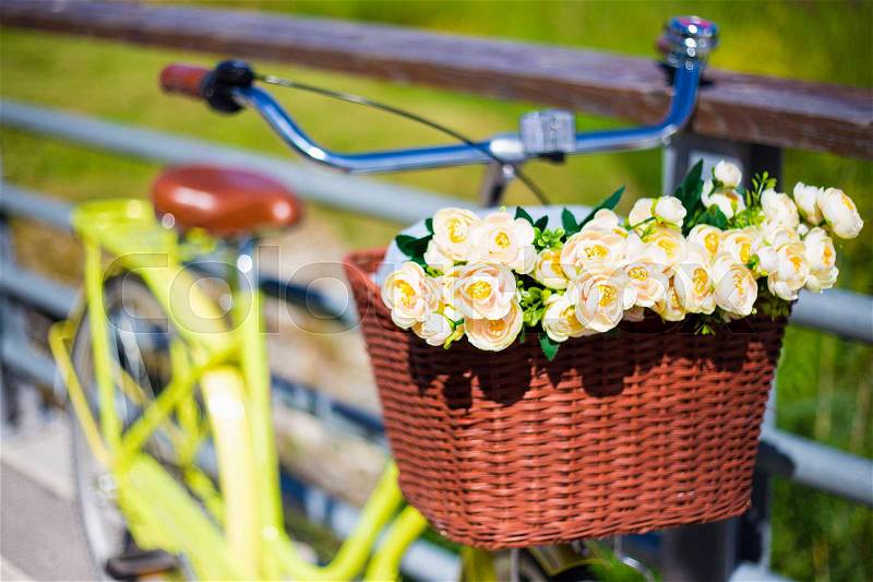 Retro bicycle with wicker basket and bouquet of flowers, stock photo