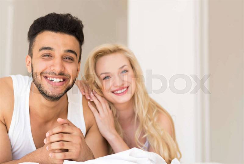 Young Couple Lying In Bed, Happy Smile Hispanic Man And Woman Lovers In Bedroom, stock photo