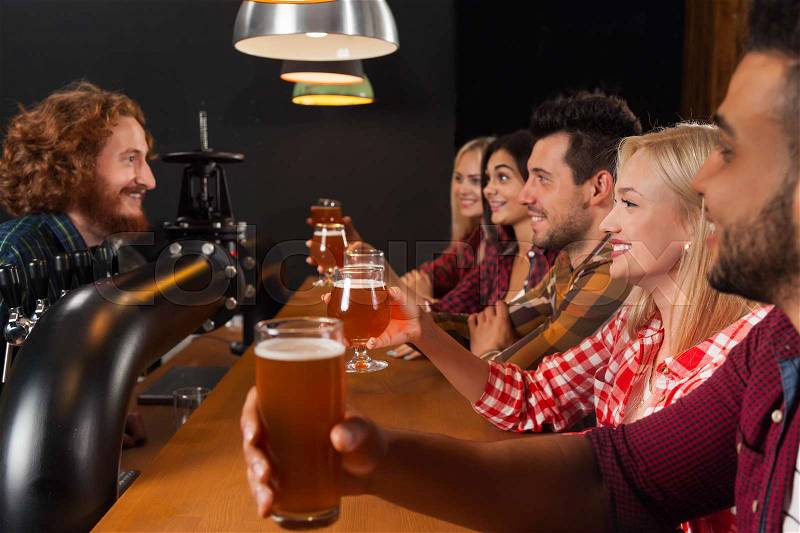 Young People Group In Bar, Hold Beer Glasses, Friends Sitting At Wooden Counter Pub, Friends Toast, Communication Party Celebration, stock photo