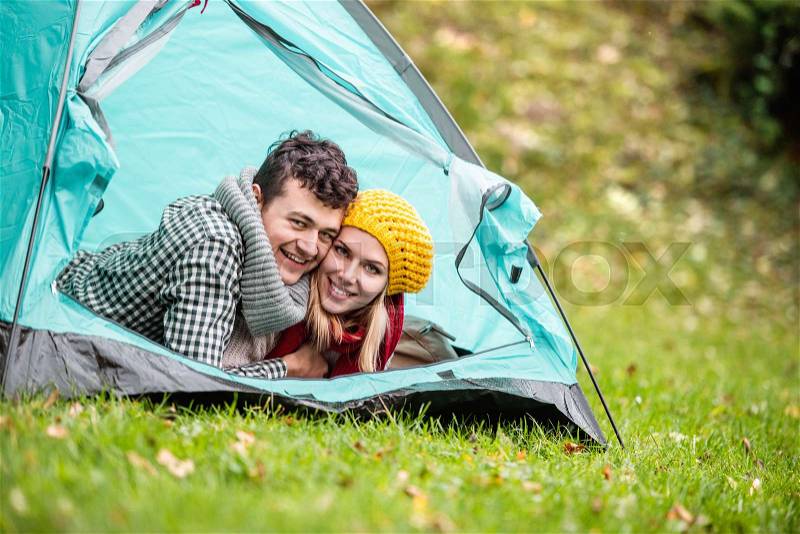 Beautiful young couple lying in tent, camping in autumn nature, stock photo