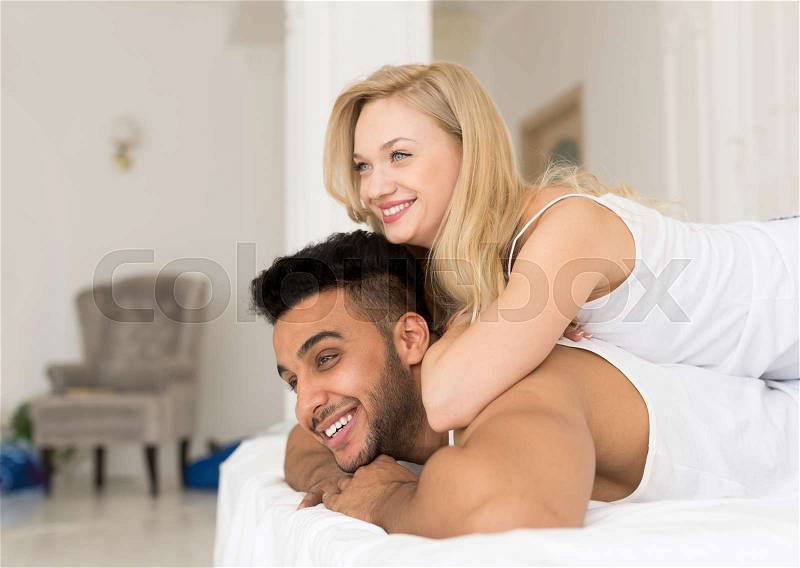 Young Couple Lying In Bed, Happy Smile Hispanic Man And Woman Lovers In Bedroom, stock photo