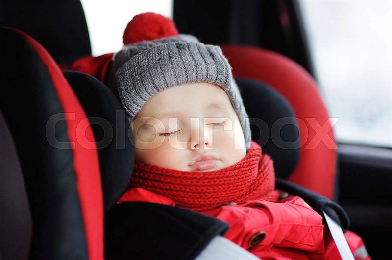 Portrait of toddler boy sleeping in car seat. Transportation safety, stock photo