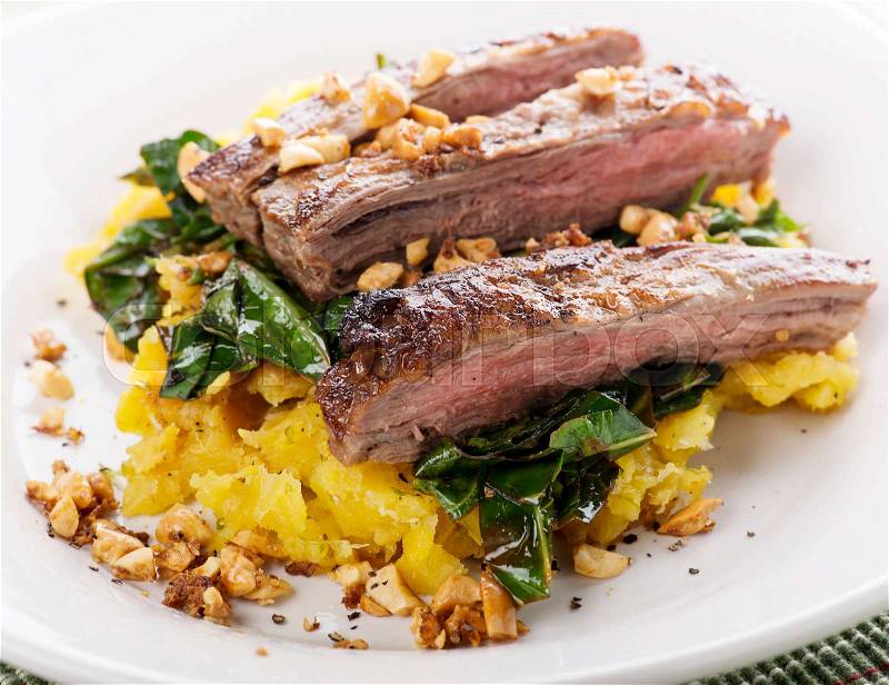 Flank steak with mashed plantain , collard greens and ginger peanuts, stock photo