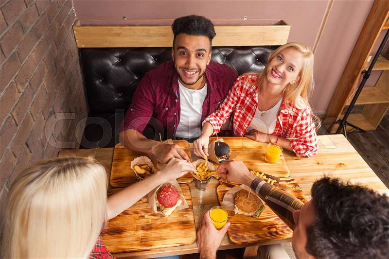 People Group Eating Fast Food Burgers Potato Sitting At Wooden Table In Cafe Top Angle View, Friends Meeting Communication, stock photo