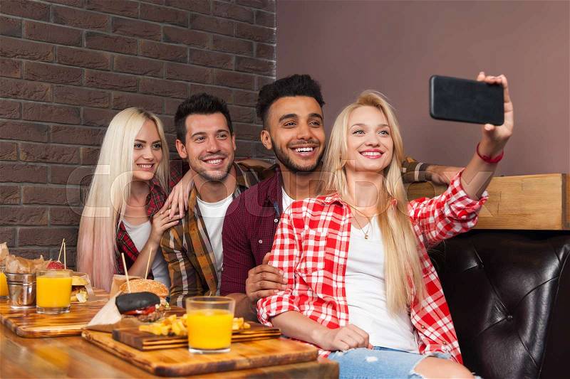 People Group Eating Fast Food Burgers Potato Sitting At Wooden Table In Cafe Taking Selfie Photo, Friends Meeting Communication, stock photo