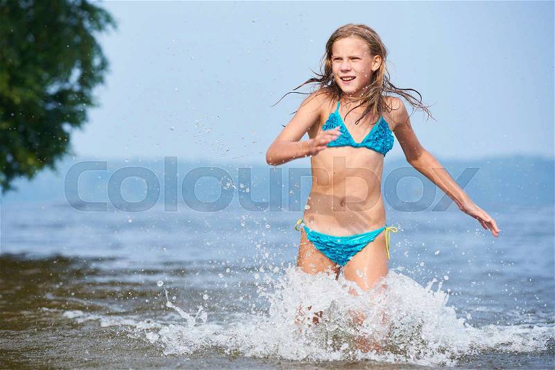 Girl teenager running on the water in the lake, stock photo
