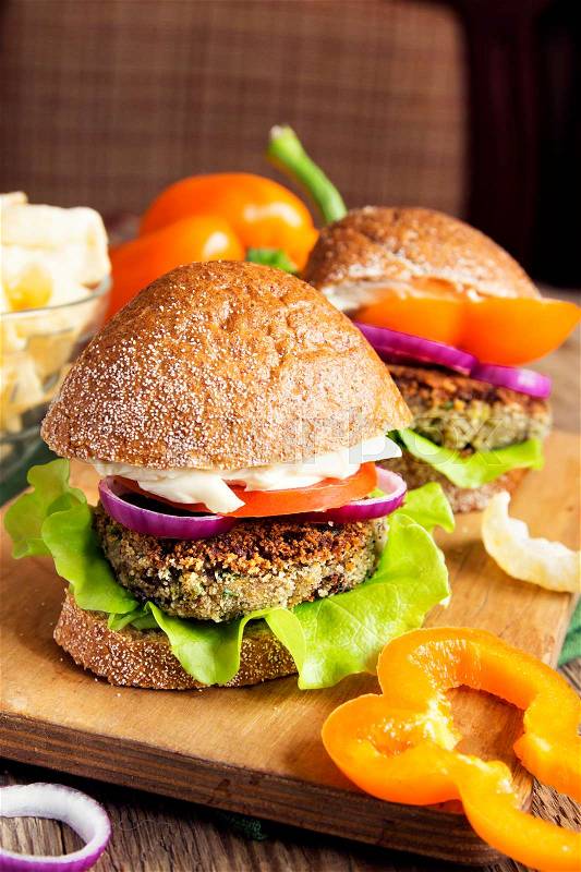 Vegetarian lentil burger with vegetables on wooden cutting board - heathy tasty vegetarian snack (food, lunch), stock photo
