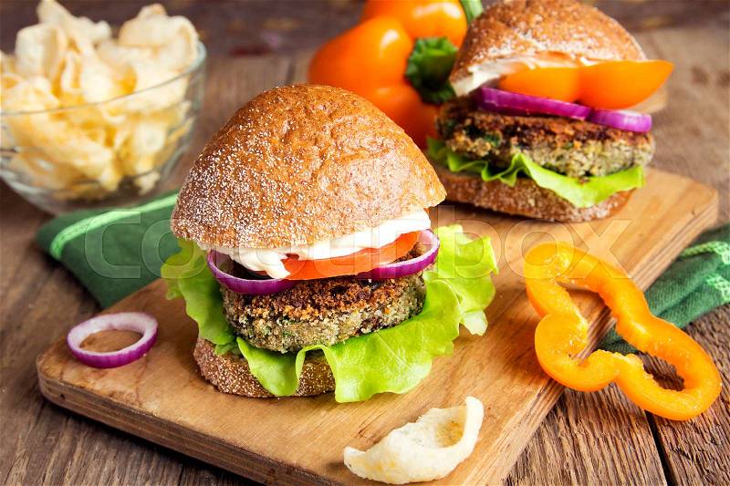 Vegetarian lentil burger with vegetables on wooden cutting board - heathy tasty vegetarian snack (food, lunch), stock photo