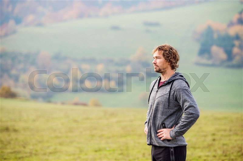 Handsome young man running outside in sunny autumn nature, resting, stock photo