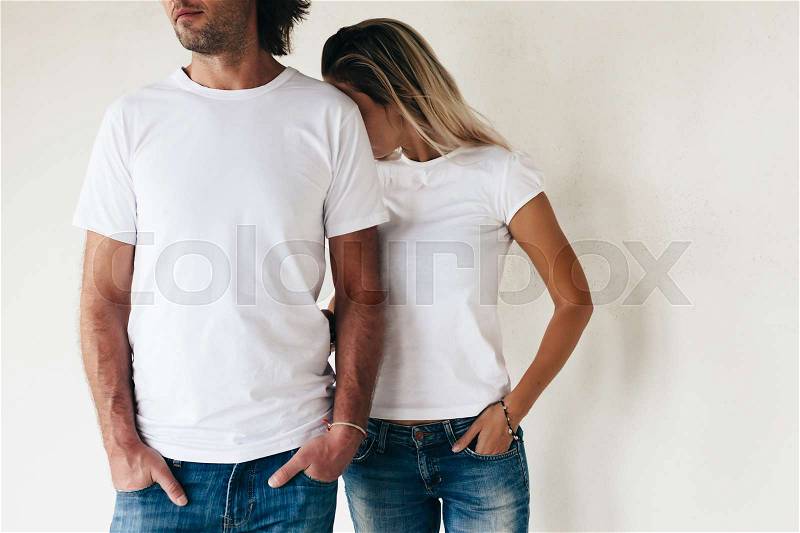 Two models man and woman wearing blanc t-shirt posing against white wall, toned photo, front tshirt mockup for couple, stock photo