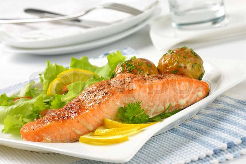 Pan seared salmon fillet served with roasted potatoes and fresh vegetables, stock photo