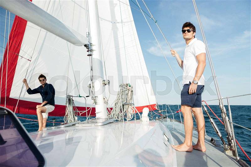 Two young handsome happy men friends standing on the yacht, stock photo