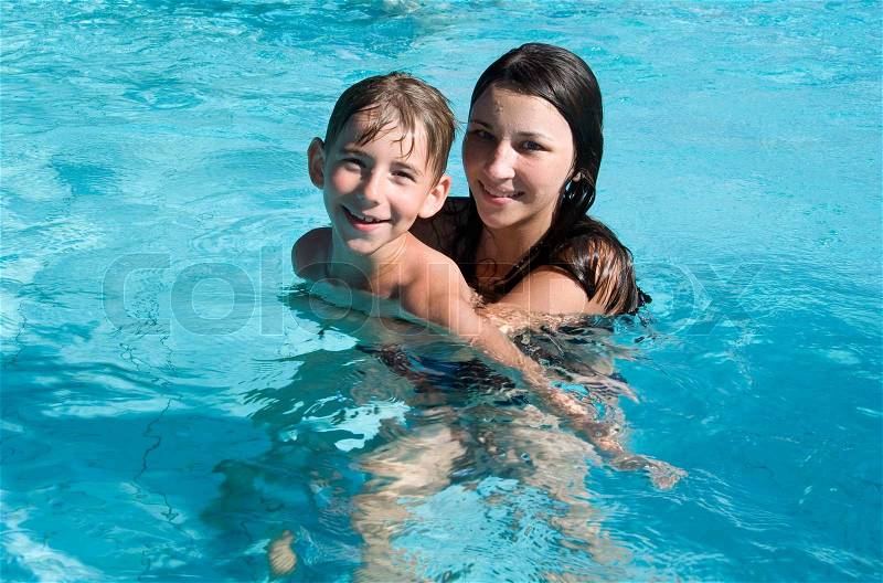 Smiling children in the swimming pool of water park in sunny summer day, stock photo