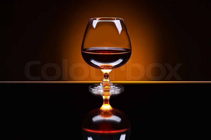 Snifter with brandy on a reflective background, stock photo