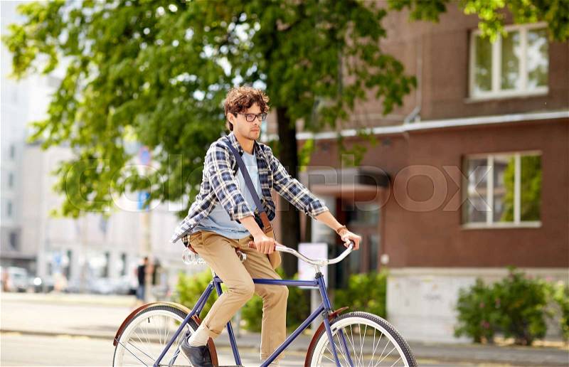 People, style, leisure and lifestyle - young hipster man with shoulder bag riding fixed gear bike on city street, stock photo