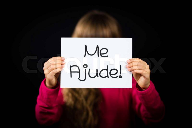 Studio shot of child holding a sign with Portuguese words Me Ajude - Help Me, stock photo