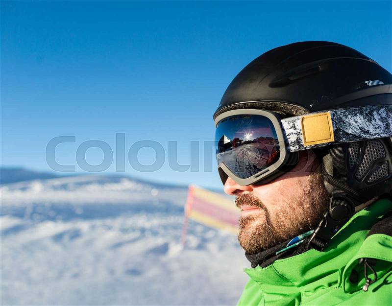 Close-up of male skier with large oversized ski goggles standing on the top of a mountain ready for skiing, stock photo