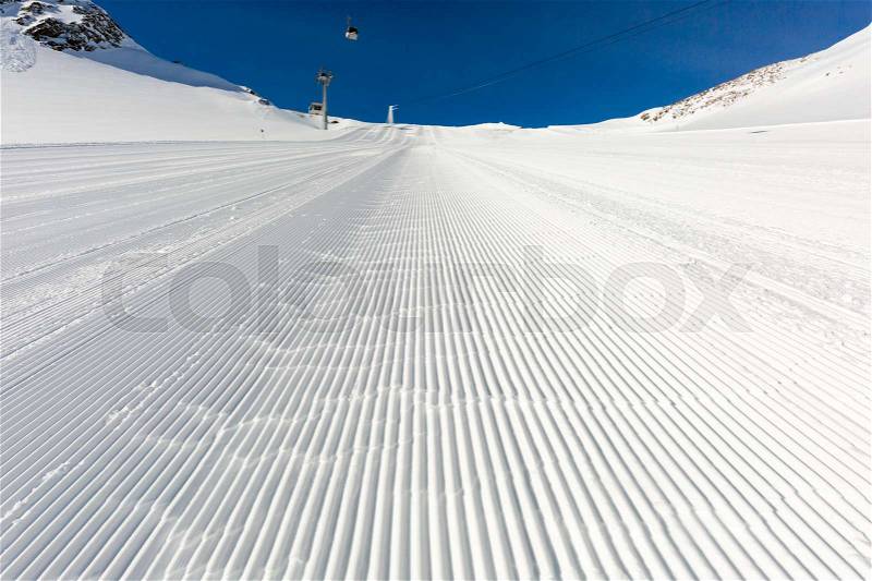 Fresh snow at recently groomed ski run at ski resort in the Alps on a sunny winter day, stock photo
