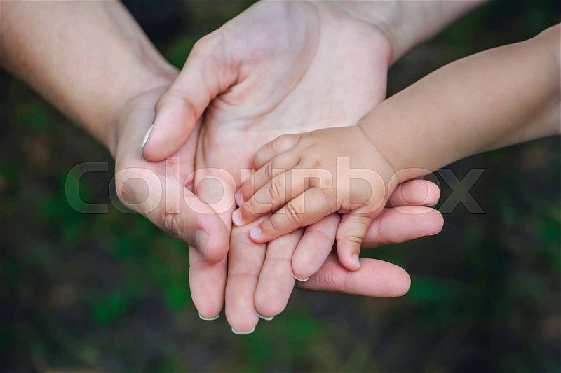 Three hands of the same family - father, mother and baby stay together. Close-up. The concept of family unity, protection, support, prosperity, love and parental happiness, stock photo