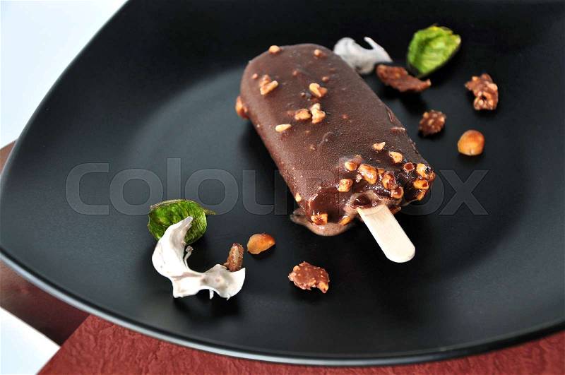 Chocolate ice cream bar melting on black plate, stock photo