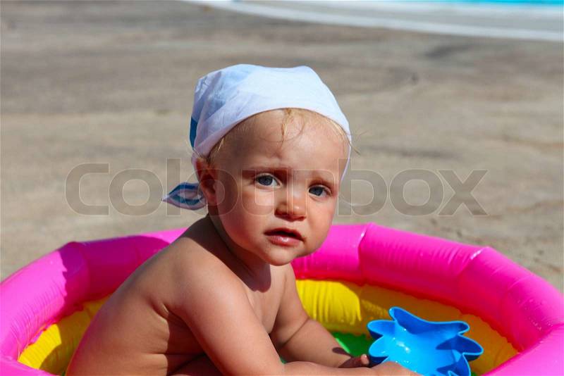 Baby girl playing in a colorful kiddie pool, stock photo