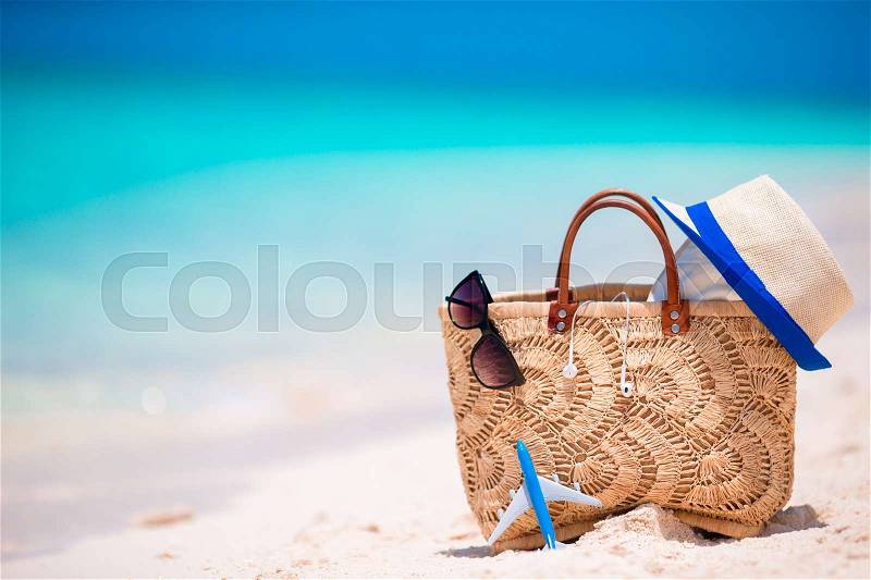 Beach accessories - straw bag, headphones, toy plane and sunglasses on the beach, stock photo