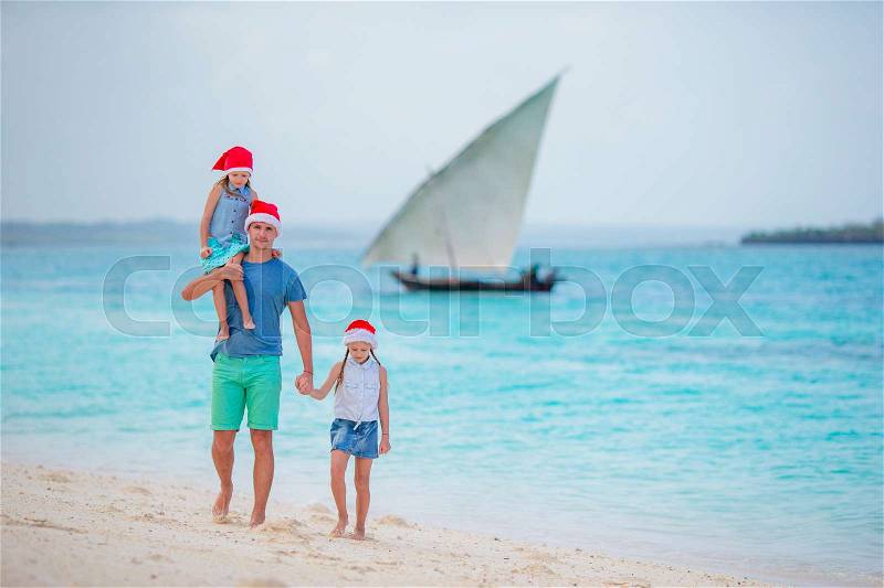 Happy family in Santa Hats on summer vacation. Christmas holidays with young family of four enjoying their sea trip, stock photo