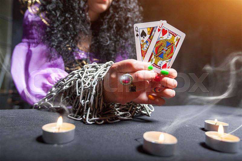 Sorceress with her hands loaded with chains telling fortunes using cards, stock photo