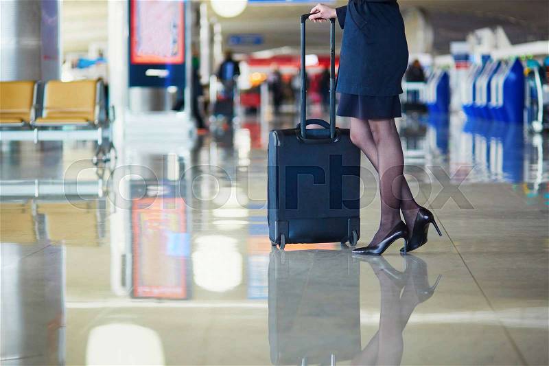 Beautiful female passenger or flight attendant in international airport with hand luggage, stock photo