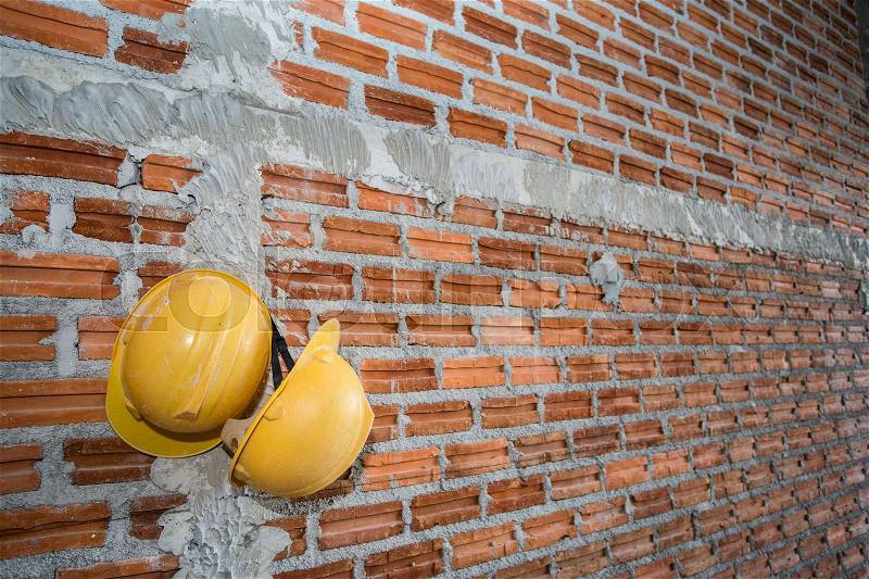 Brick wall with yellow safety helmet, stock photo