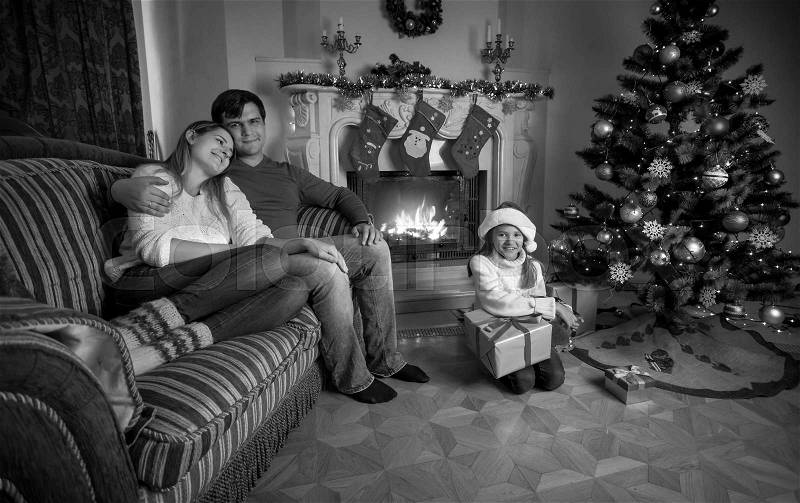 Black and white image of happy young family relaxing near fireplace on Christmas, stock photo