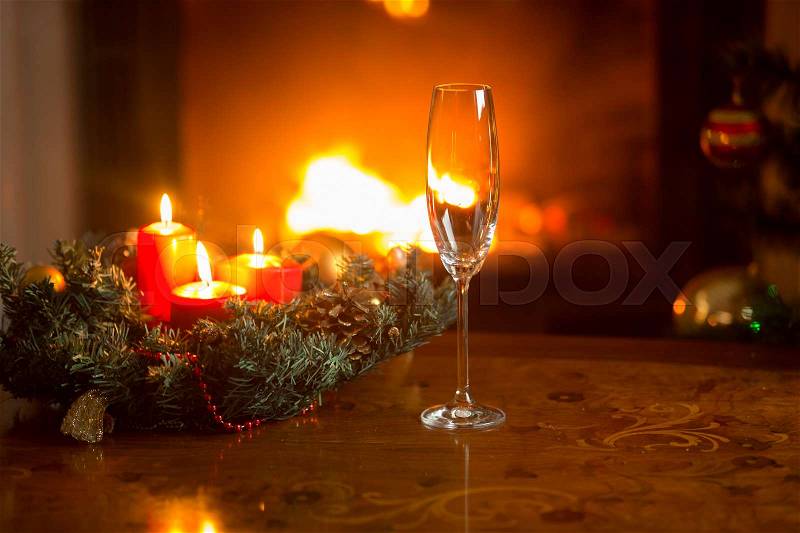 Closeup of empty champagne flute on Christmas dinner table in front of burning fireplace, stock photo