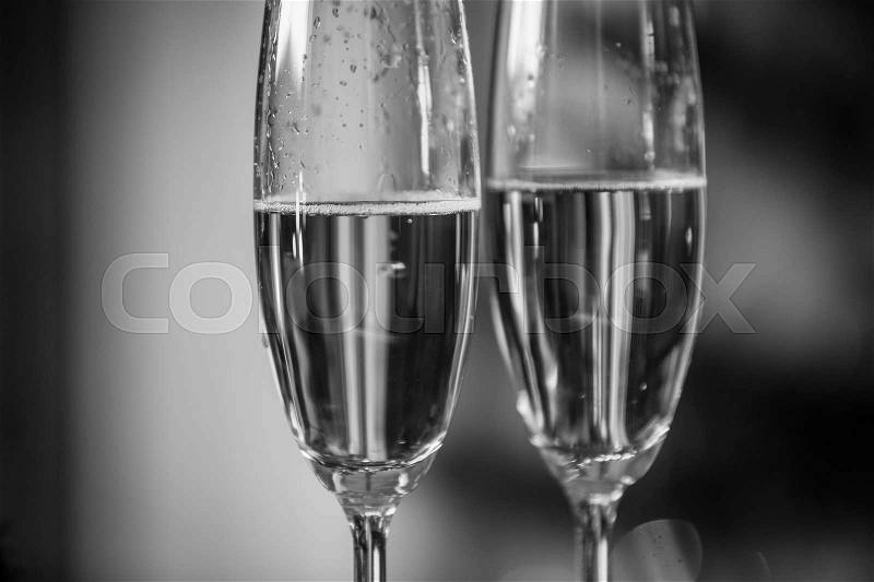 Macro black and white image of champagne bubbles in two glasses, stock photo