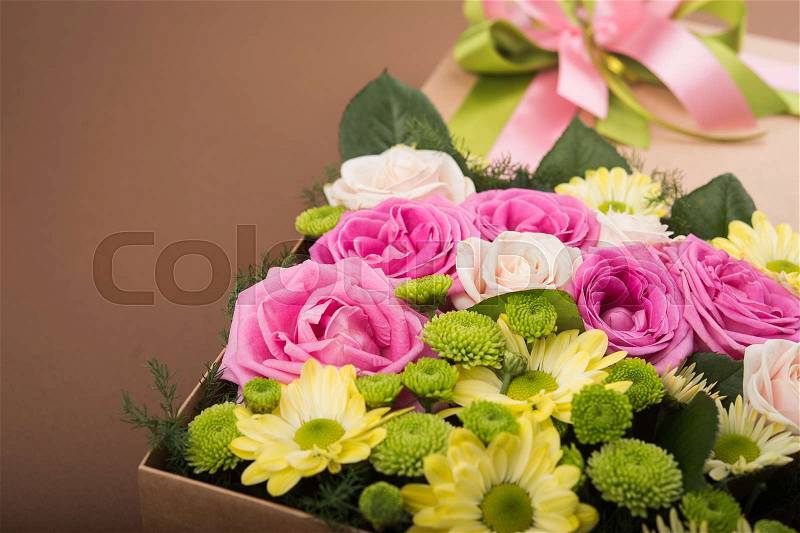 Gift box with flowers on vintage brown background, stock photo