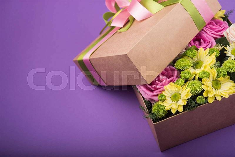 Gift box with flowers on purple background, stock photo