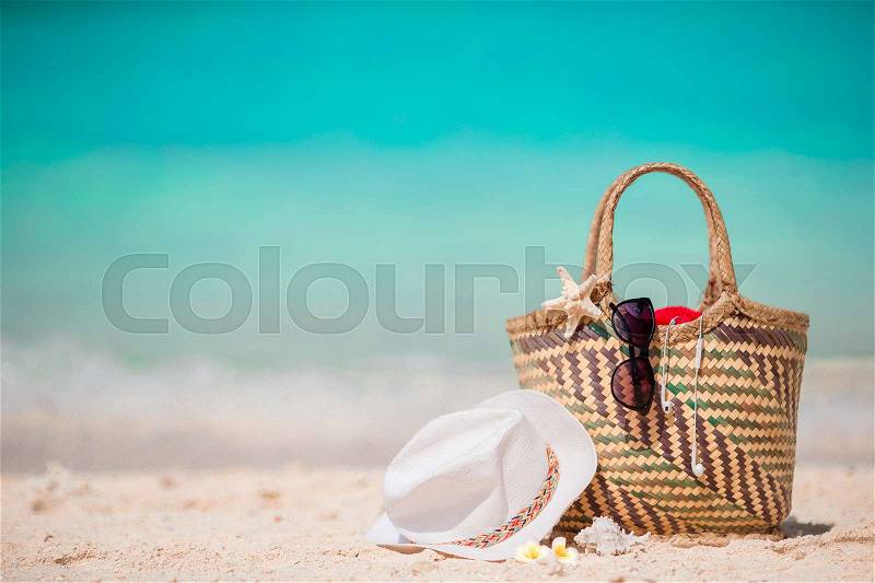 Straw bag, fist star, headphones, hat and sunglasses on white beach, stock photo