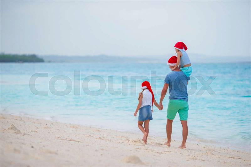 Happy family in Santa Hats on summer vacation. Christmas holidays with young family of four enjoying their sea trip, stock photo