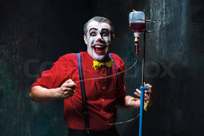 The scary clown and drip with blood on dack. Halloween concept of horror and murderer, stock photo
