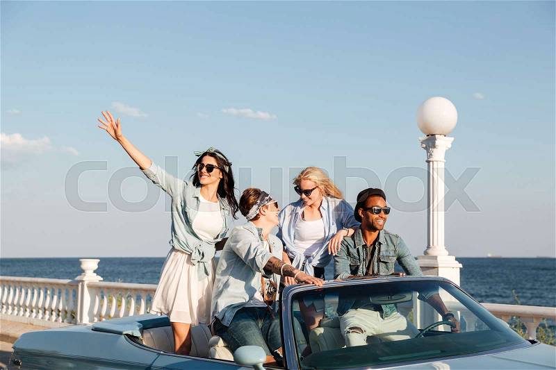 Group of happy young people laughing and driving car, stock photo