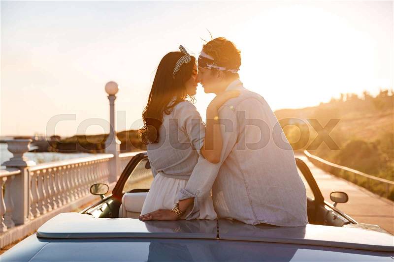 Sensual young couple sitting and kissing in car on sunset, stock photo