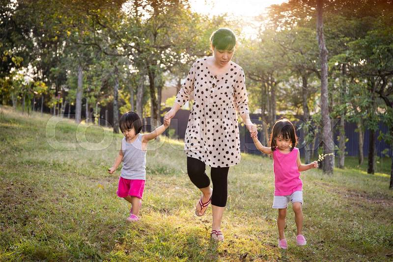 Asian Mom and Daughters Walking in the Park in the evening, stock photo